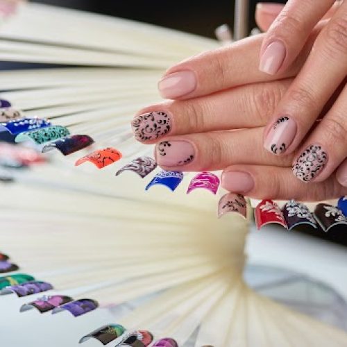 A woman's hands showcasing a fan with diverse nail designs